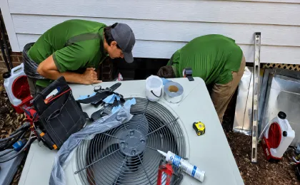 Greenergy Air technicians servicing an outdoor air conditioning condenser unit during residential HVAC maintenance