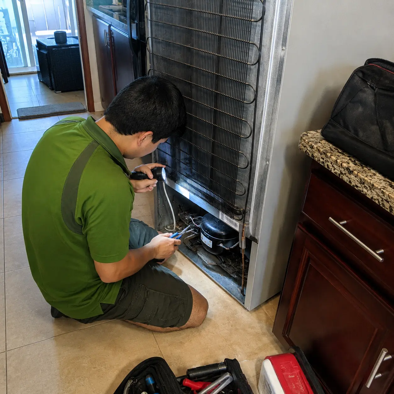 Greenergy Air technician repairing a refrigerator compressor during a professional fridge repair service