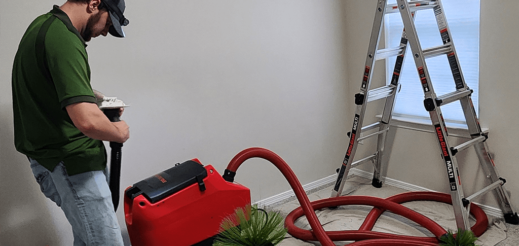 Technician operating residential air duct cleaning equipment